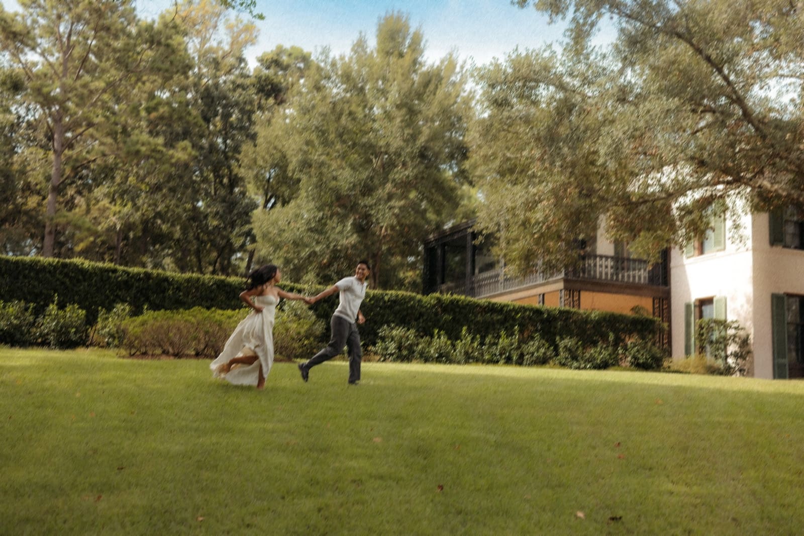 Julian and Genesis running hand in hand across a garden lawn